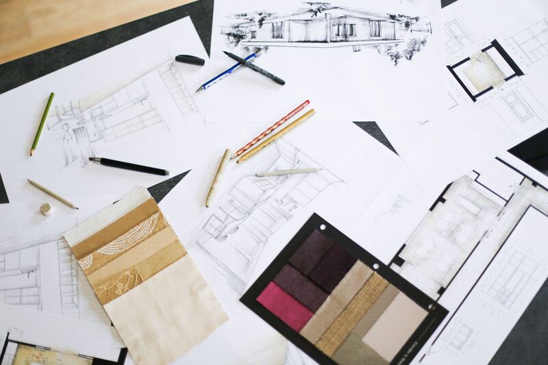 Architect's desk with hand-drawn house sketches, coloured pencils and fabric sample cards