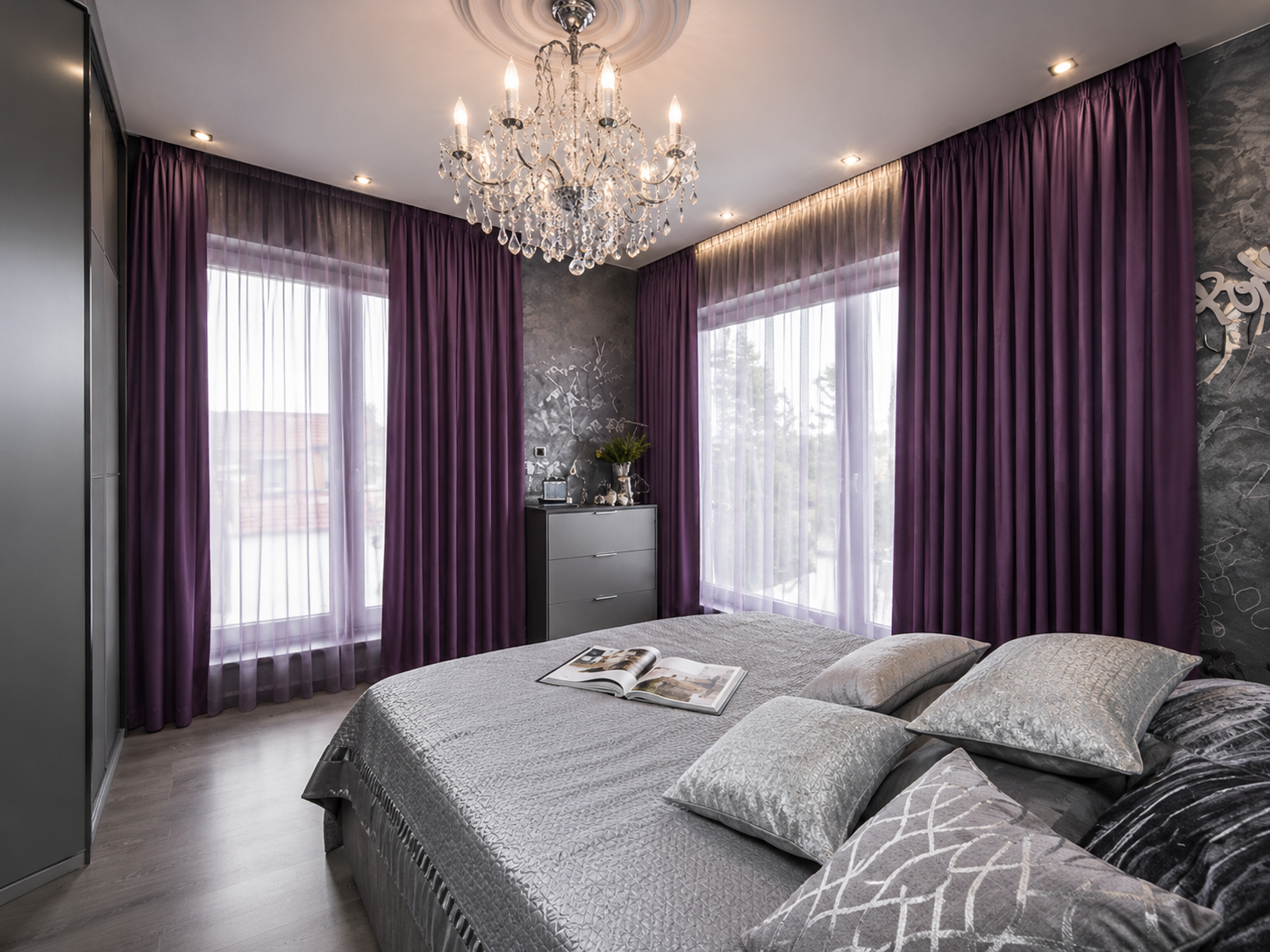 Glamorous bedroom with plum velvet curtains, crystal chandelier and grey textured wall