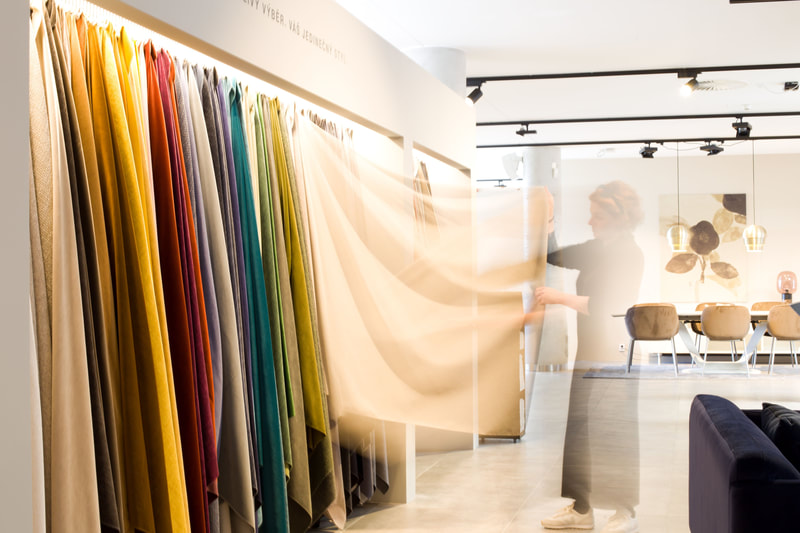 Motion-blurred figure pulling colourful curtain samples in a bright fabric and furniture showroom