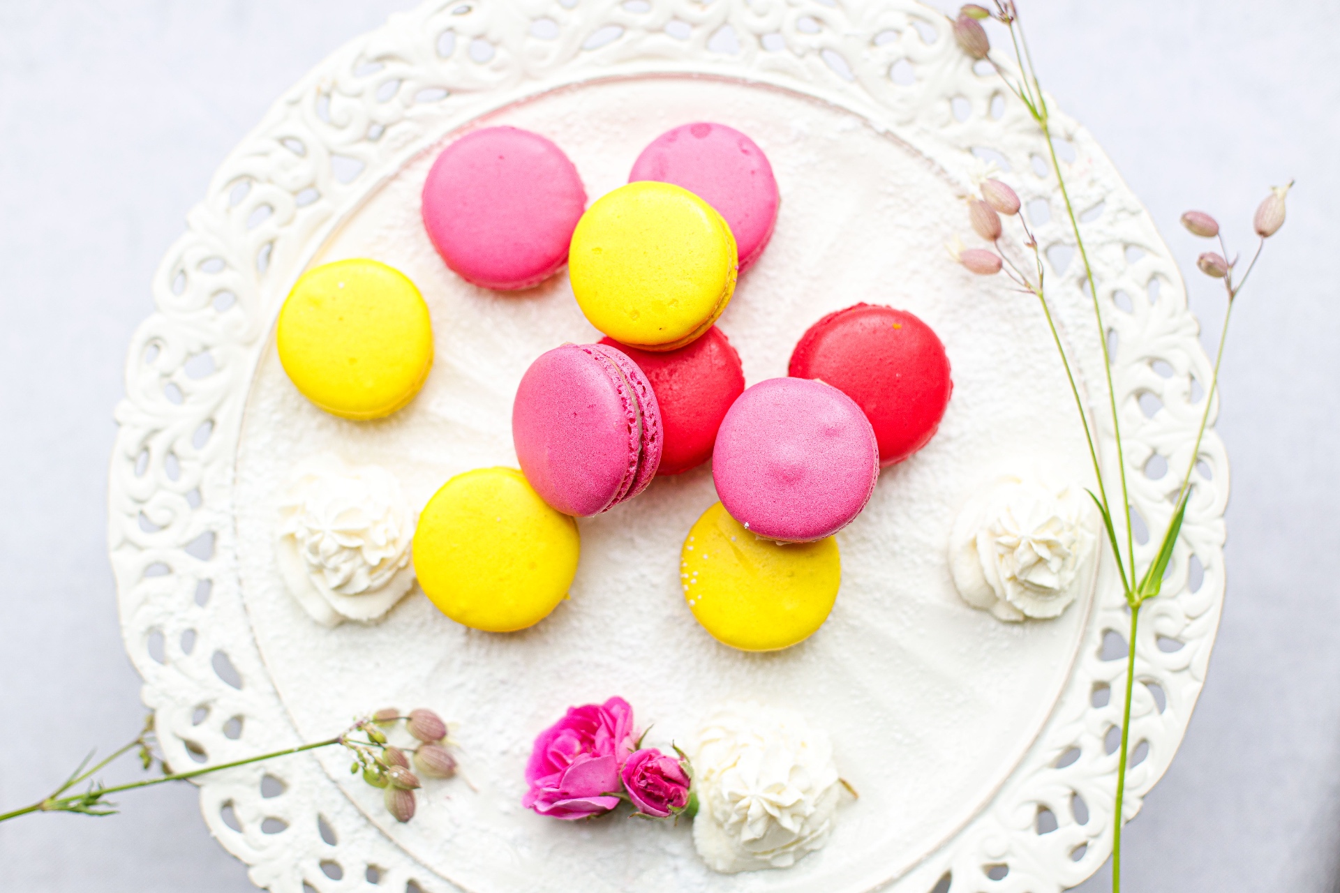 Pink and yellow macarons arranged on a plate with a lace doily